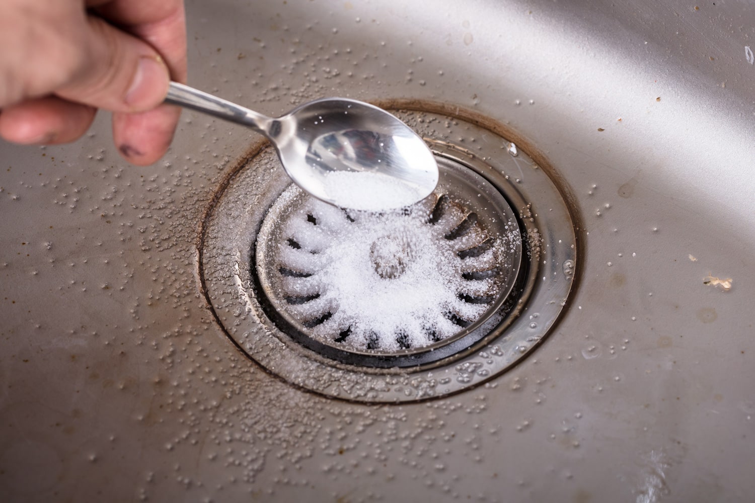 Person Putting The Baking Soda On Drain In The Washbasin