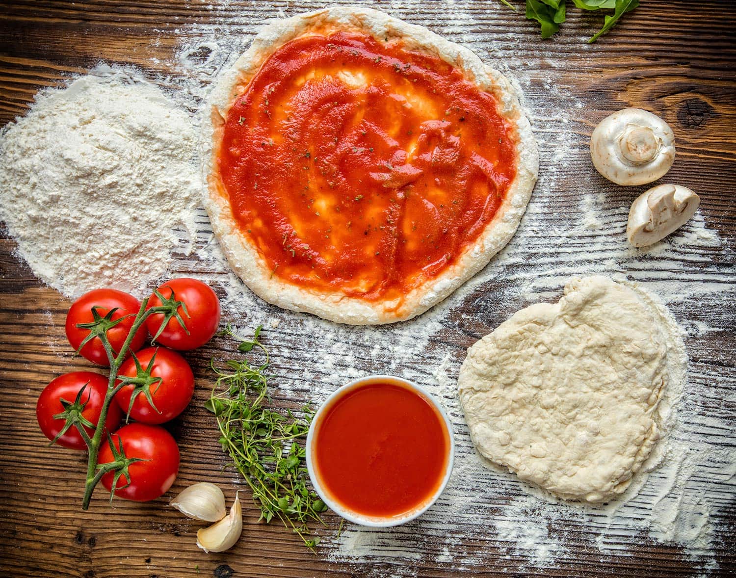 Pizza dough with ingredients and tomato sauce served on rustic wooden table