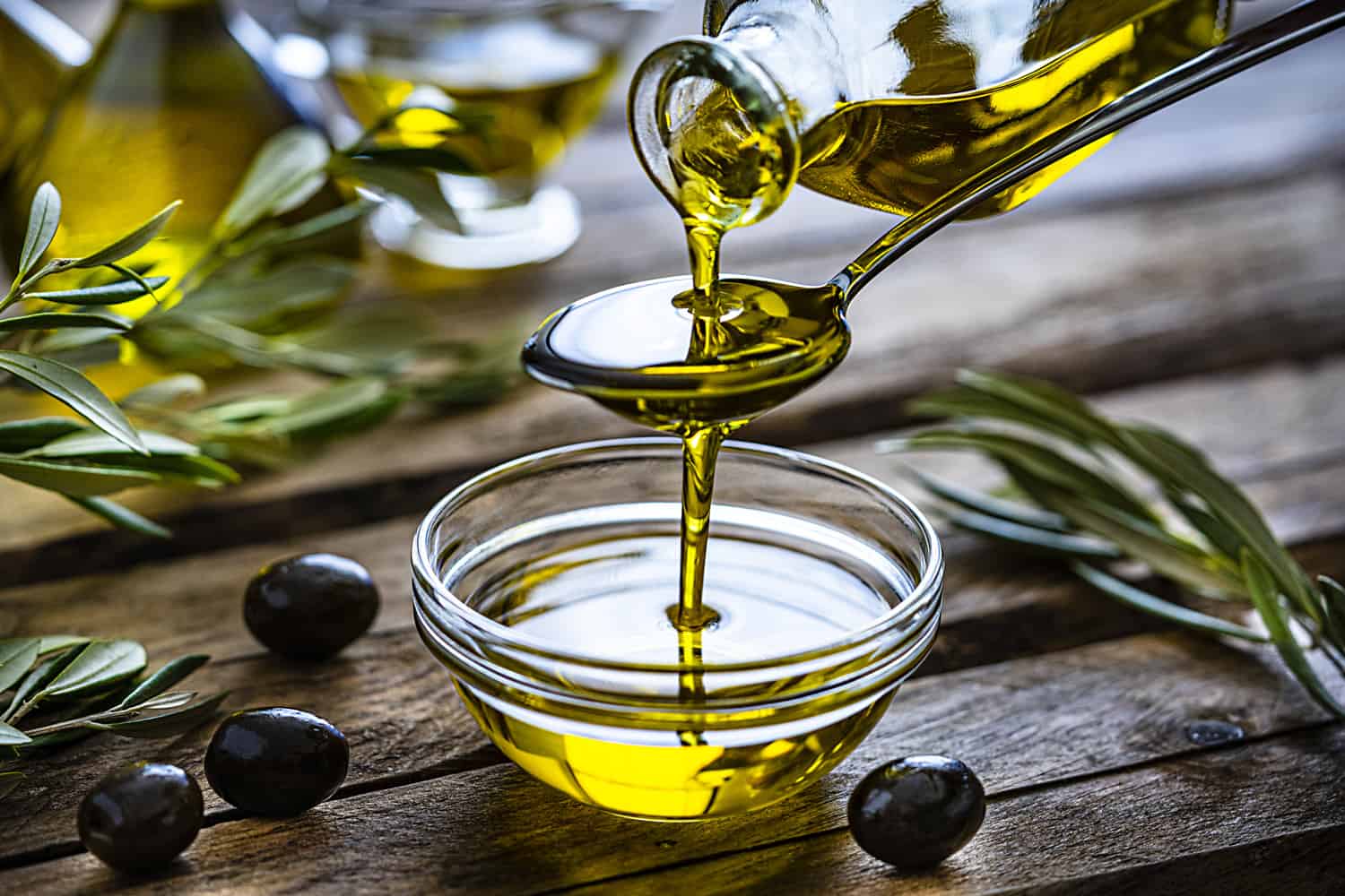 Pouring extra virgin olive oil in a glass bowl 