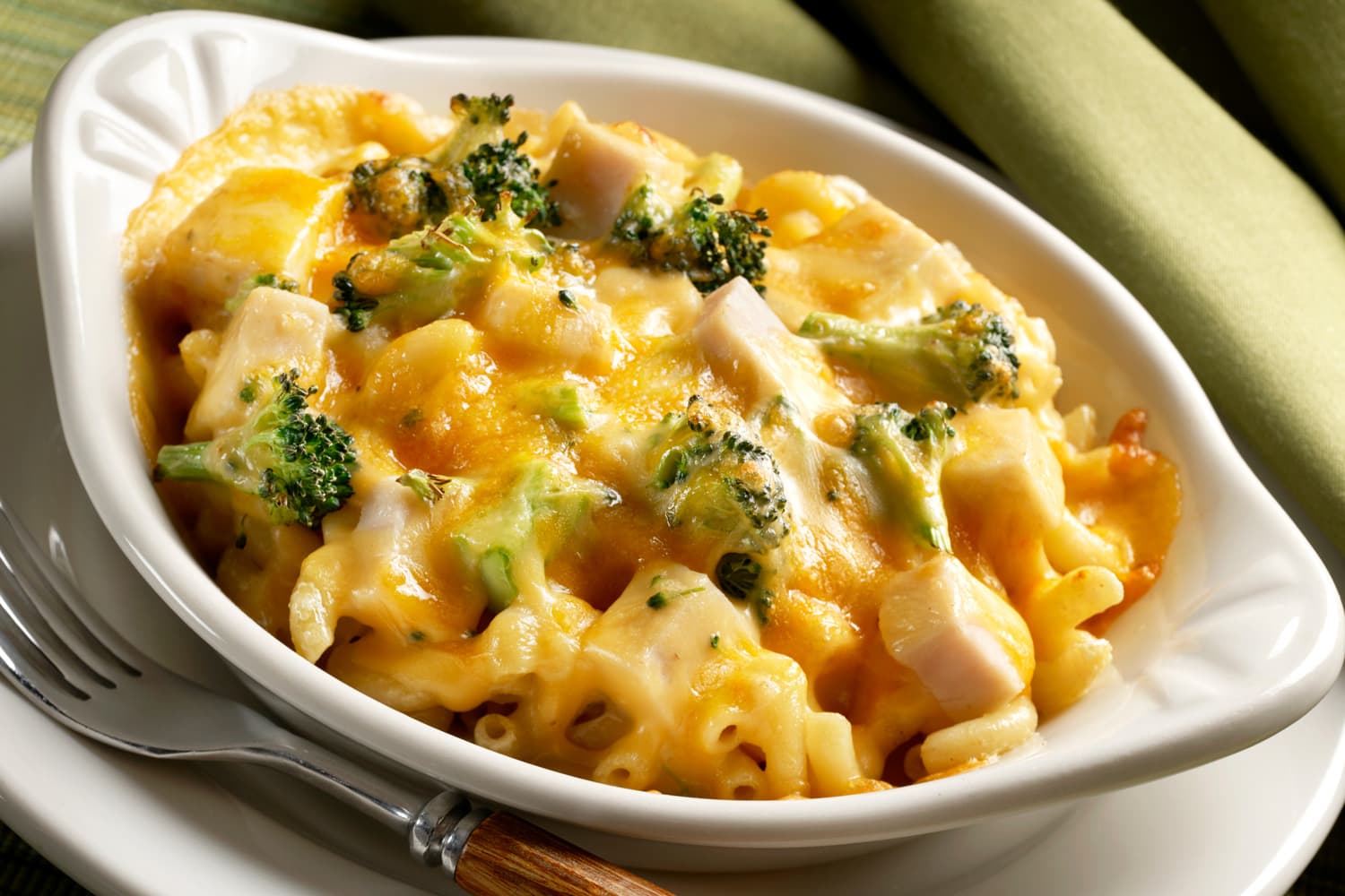 Single serve casserole of baked elbow macaroni with chopped broccoli and cubed chicken breast topped with cheddar cheese and backed until hot and melted