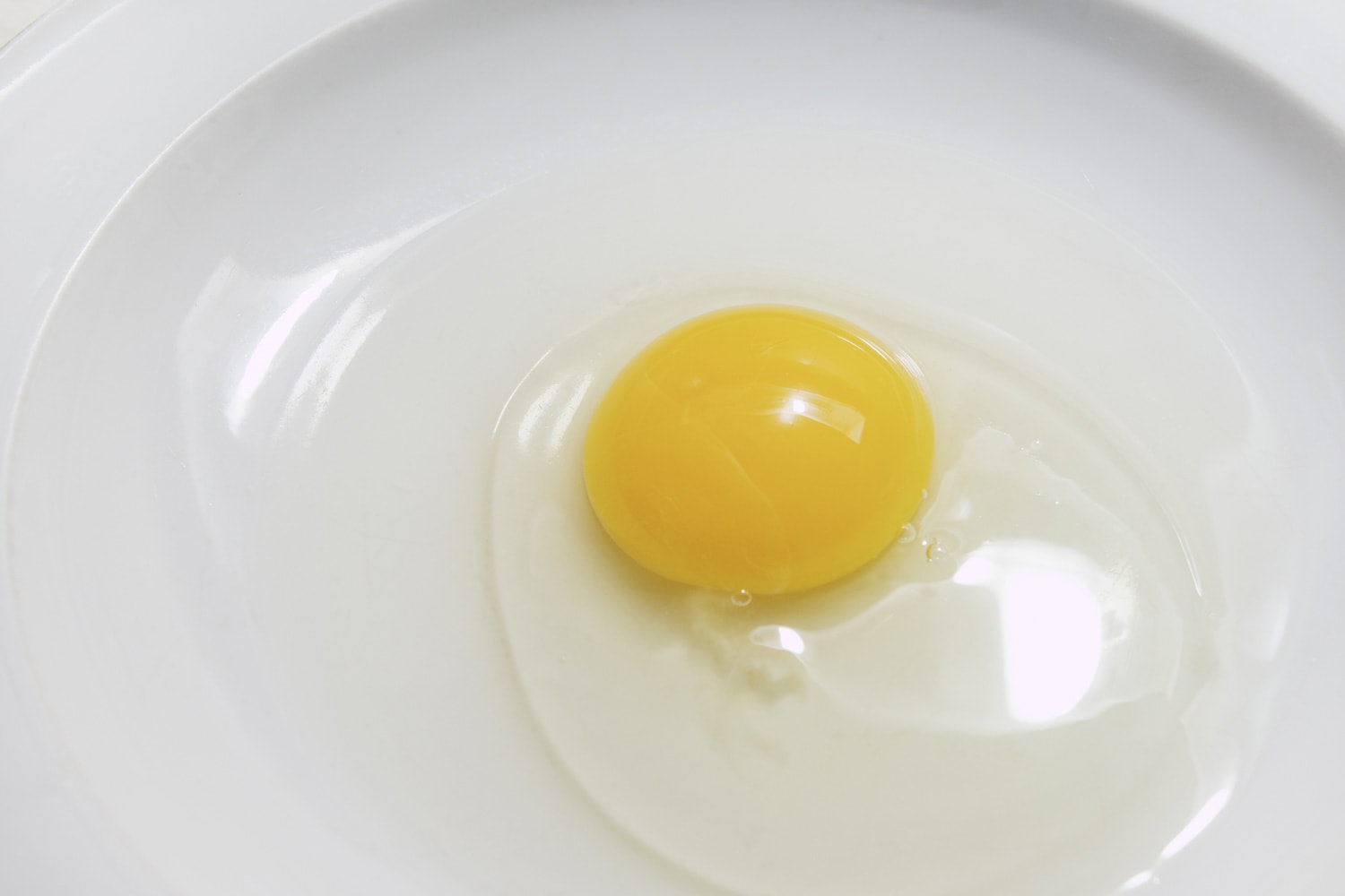 Stale eggs with rupture broken egg yolk and watery egg white in a white plate on white background. isolated broken stale egg.photo