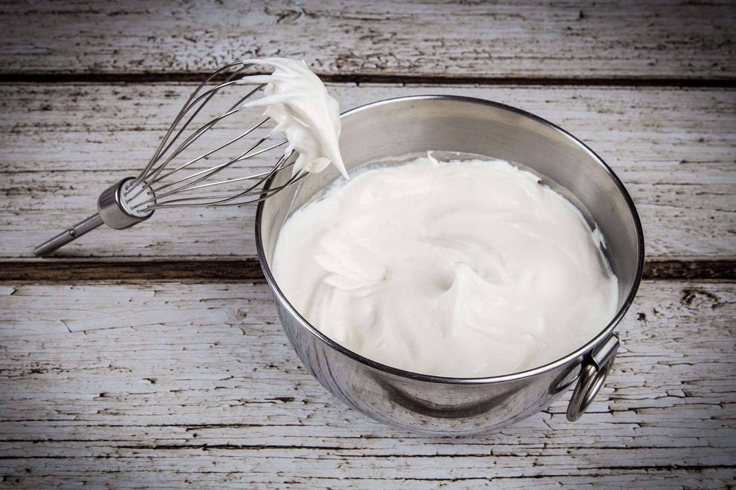 Whipped cream in bowl with and whisk