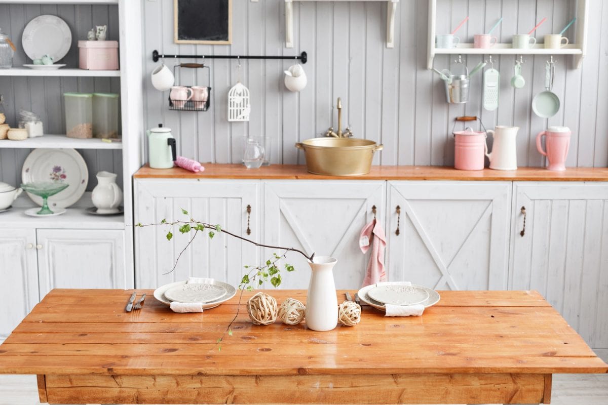 White wooden kitchen cabinets, wooden countertop and bohemian kitchen utensils