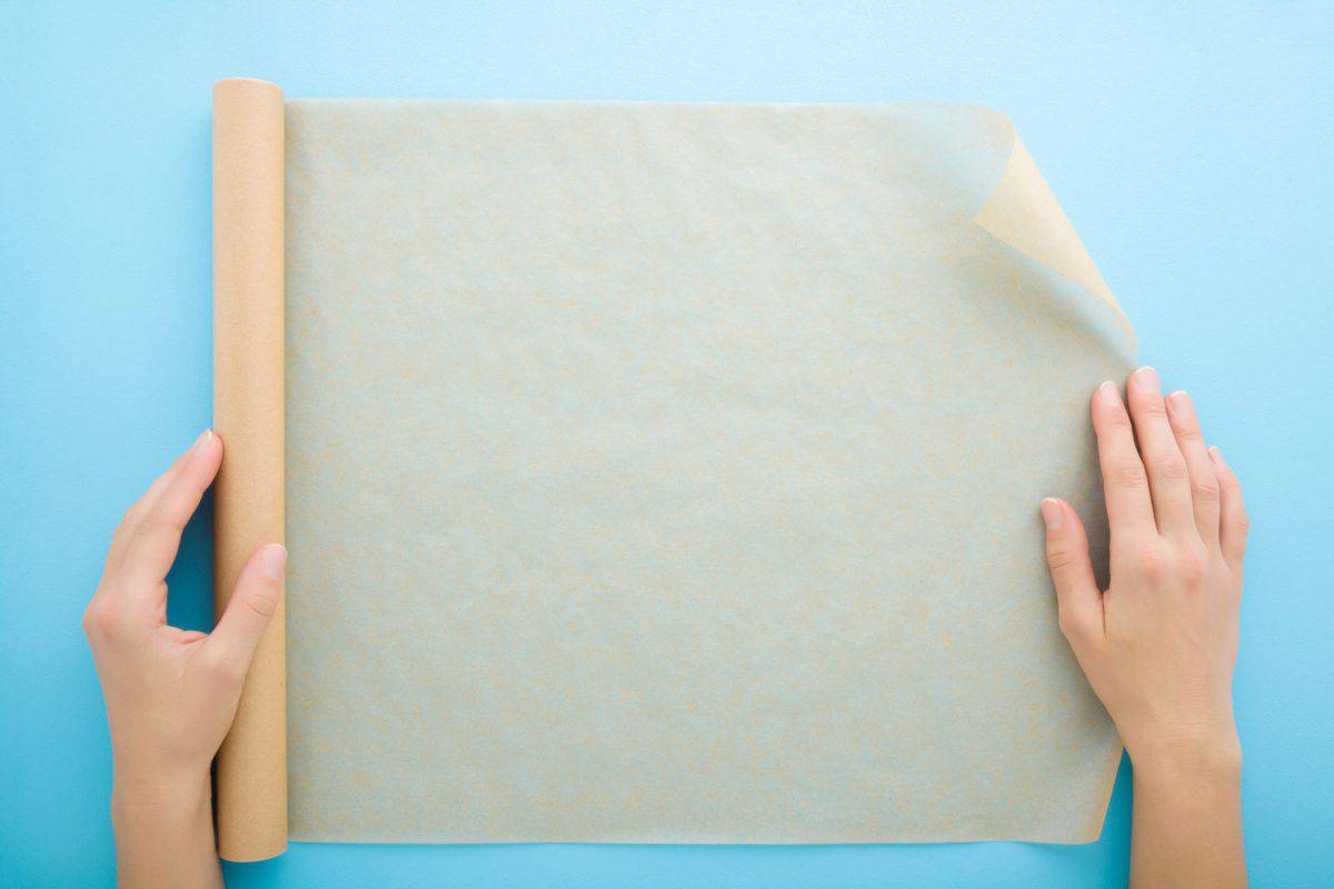 Woman unrolling parchment paper on a blue table