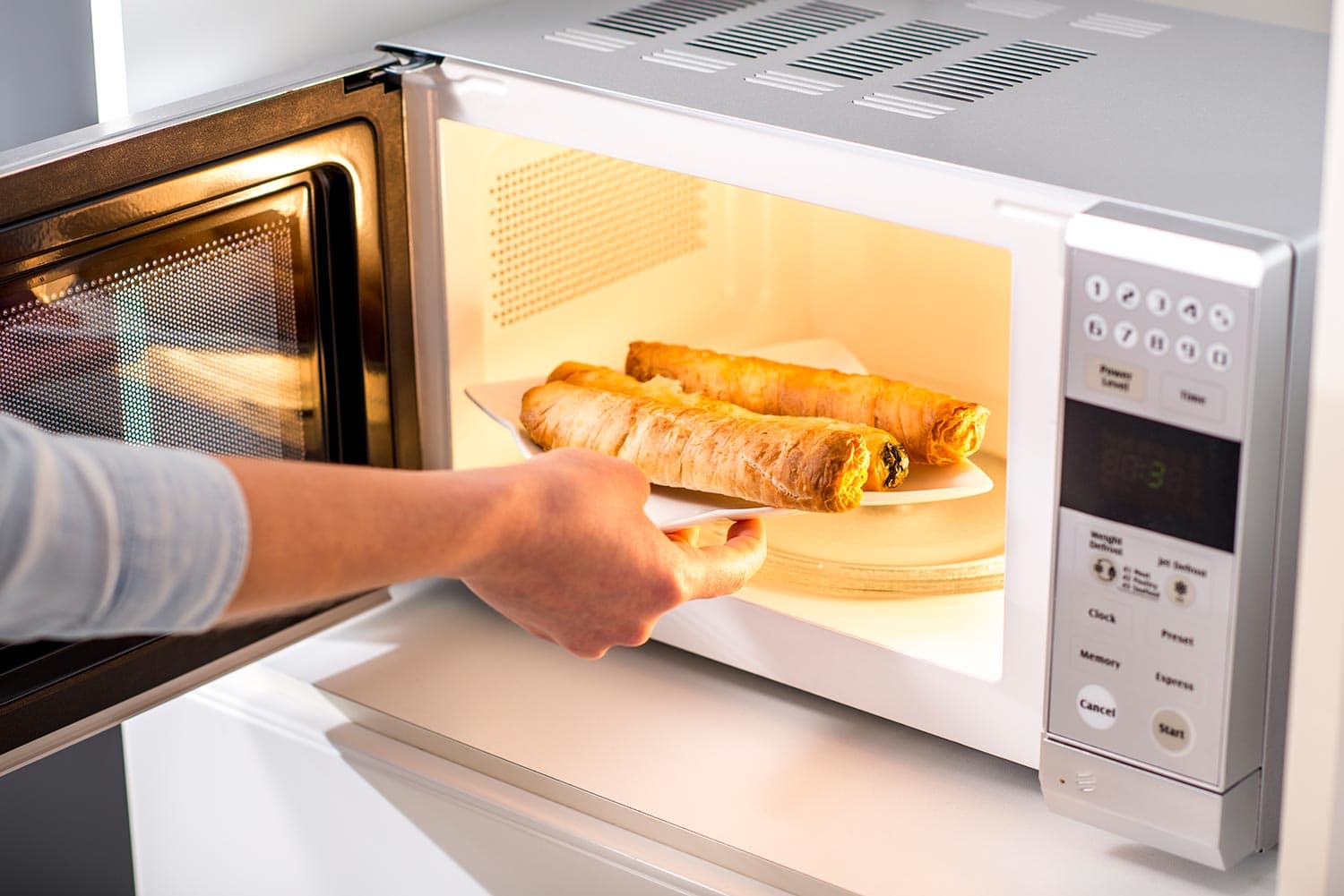 A woman baking pastry in microwave oven