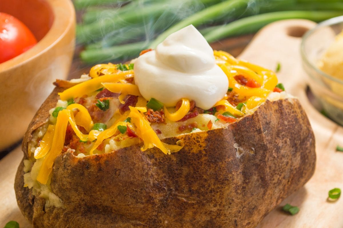 A freshly baked potato with cheese, chives and bacon
