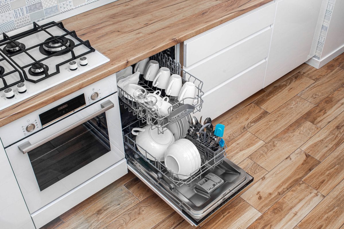 An opened dishwasher with lots of dishes inside