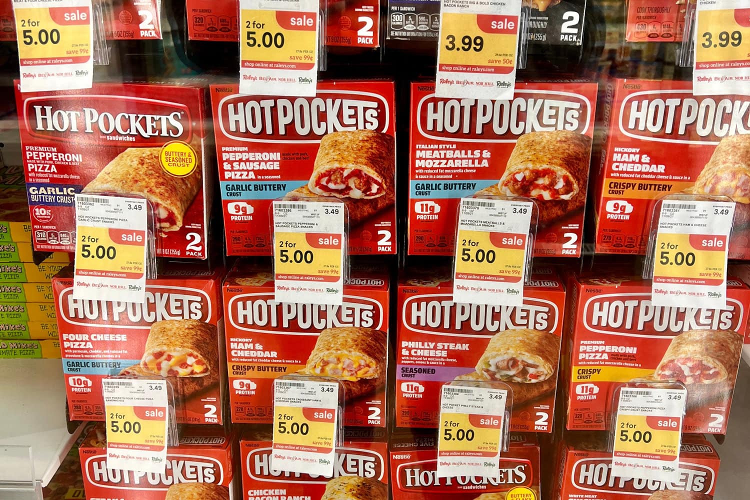 Boxes of Hot Pockets on sale behind a glass inside a freezer.