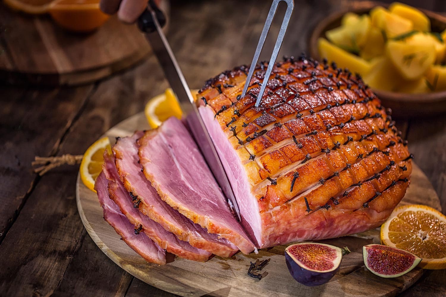 Carving glazed holiday ham with cloves