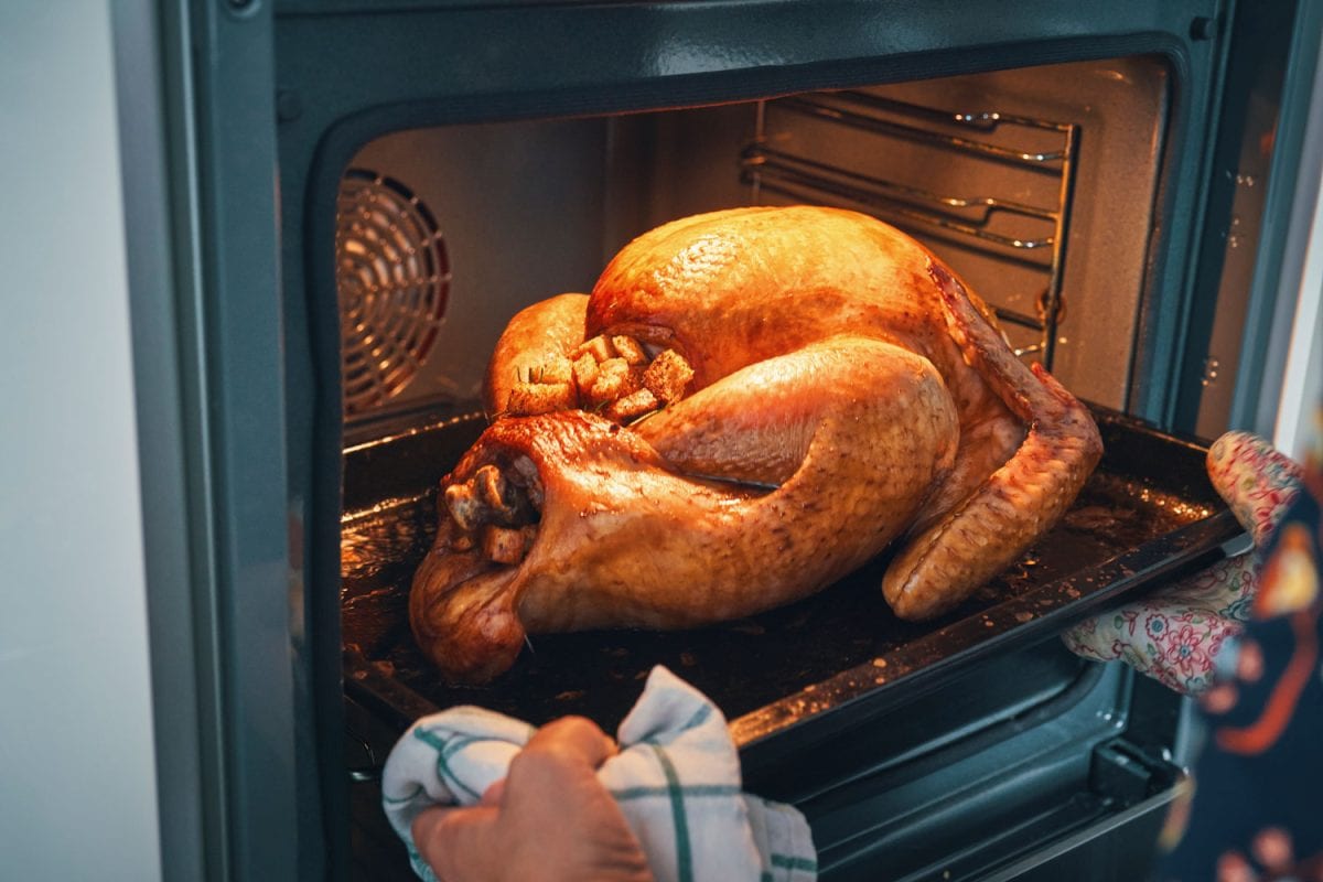 Cook removing a nicely roasted turkey from the oven