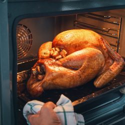 Cook removing a nicely roasted turkey from the oven, What Side Is Breast Up On A Turkey?