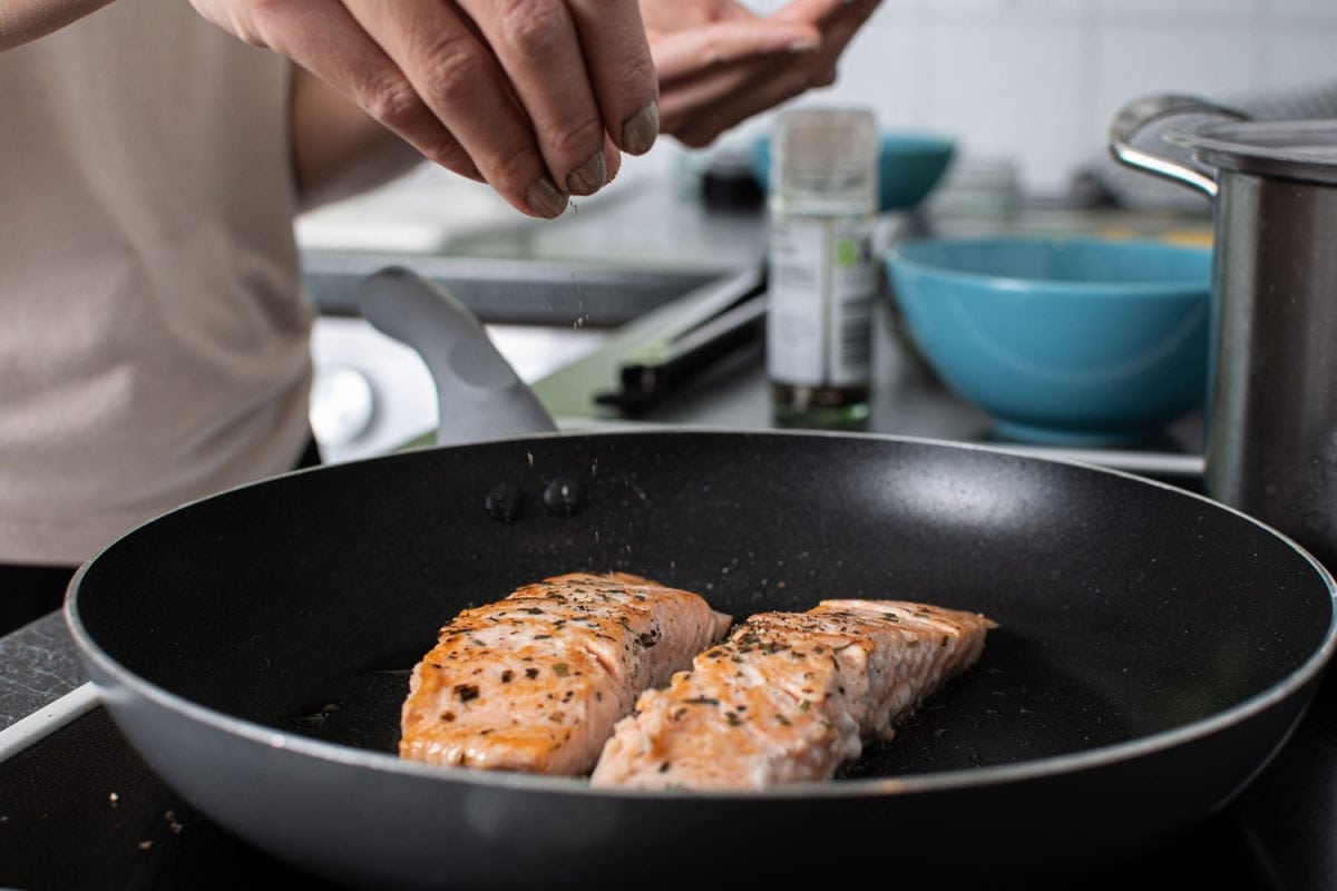 Man pouring salt and pepper to the salmon