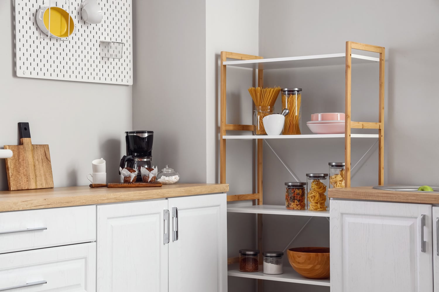 Modern shelving unit and counter with coffee maker near light wall in kitchen