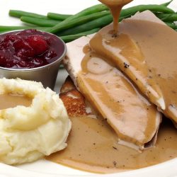 Open Face turkey sandwich with green beans, cranberry sauce and mashed potatoes with gravy pouring over potatoes and meat, Can You Make Gravy With Heavy Cream Instead Of Milk?