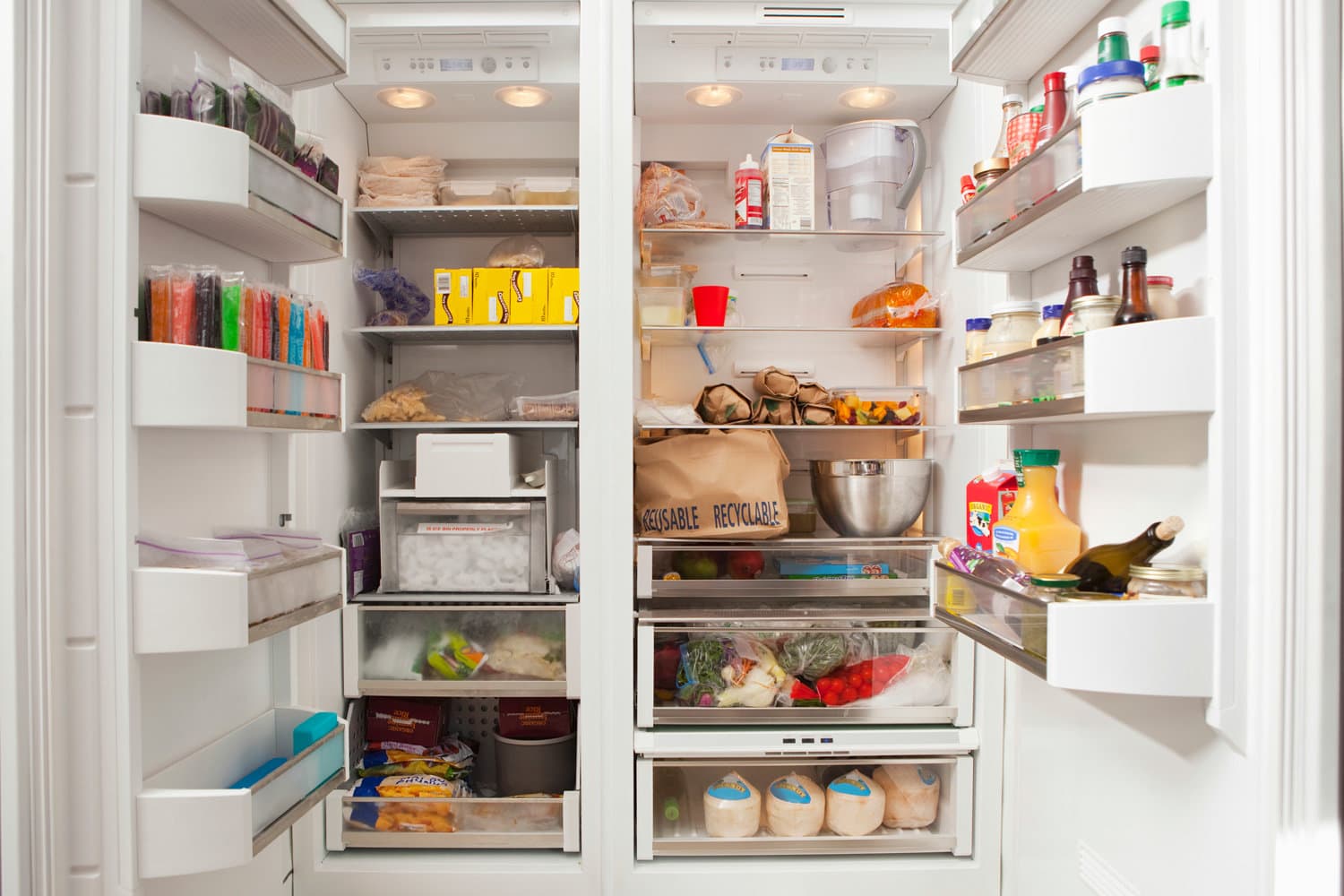 Open refrigerator with stocked food products in commercial kitchen