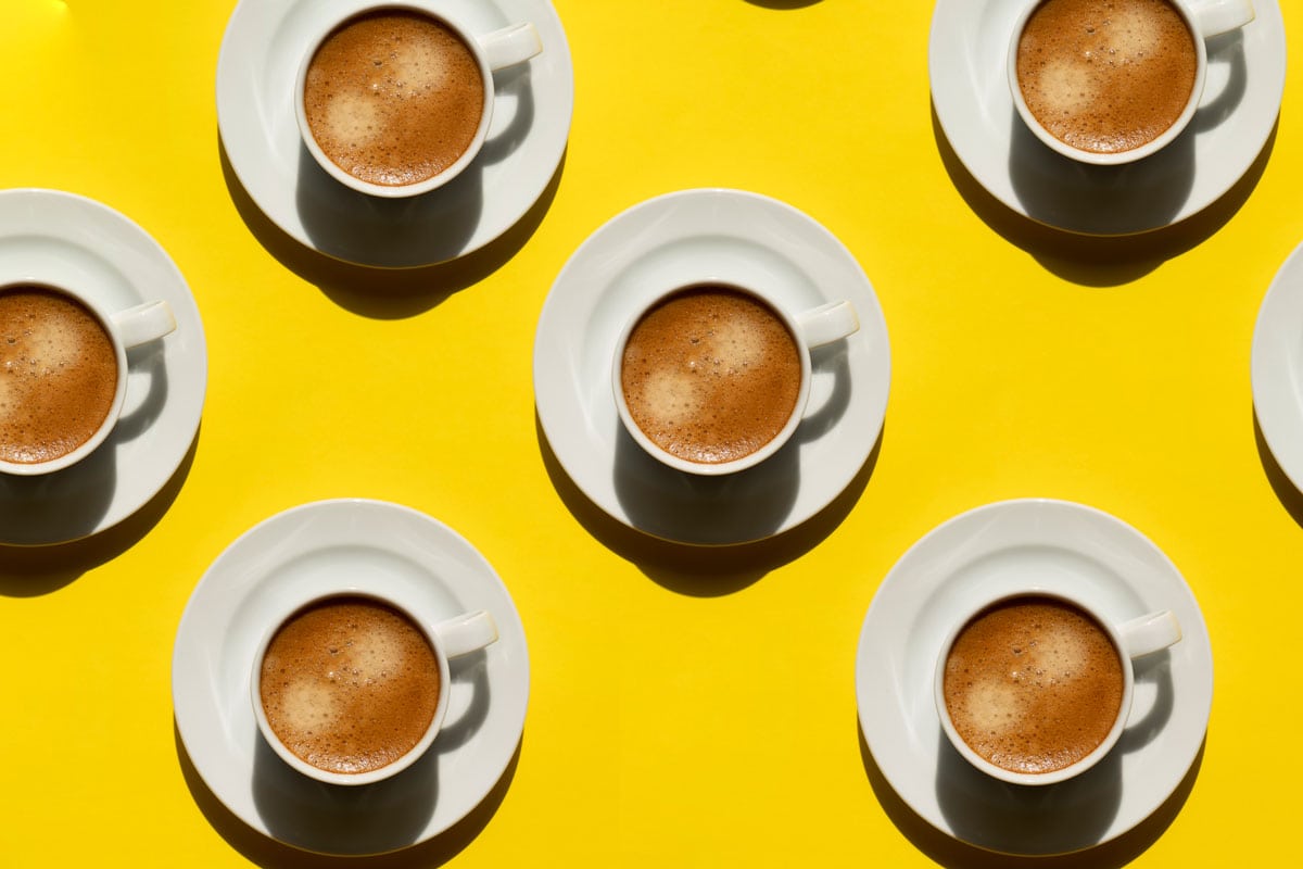 Pattern made of cup of cappuccino on yellow