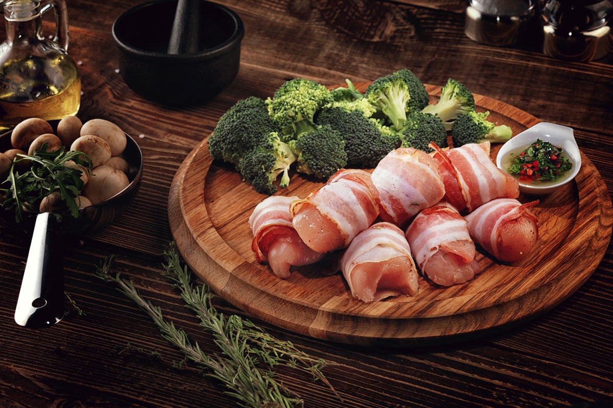 Raw rolls of turkey bacon on a wooden plate, Why Is My Turkey Bacon Slimy? [And How To Tell If Yours Has Gone Bad]