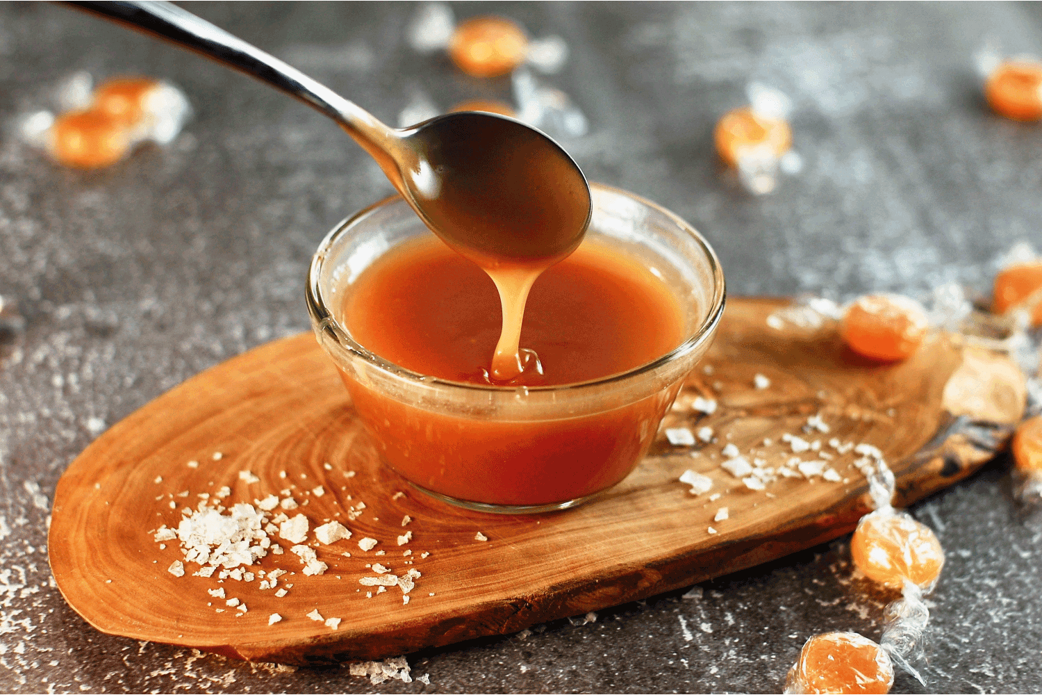 Salted caramel sauce in glass container on a wooden board, sweet sauce for desserts