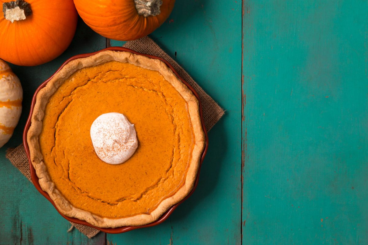 Top view of delicious pumpkin pie on a blue table