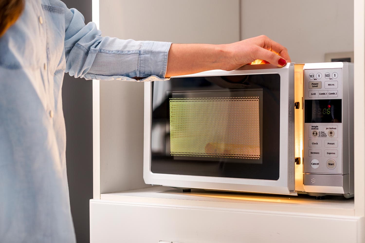 Woman hand closing microwave oven door