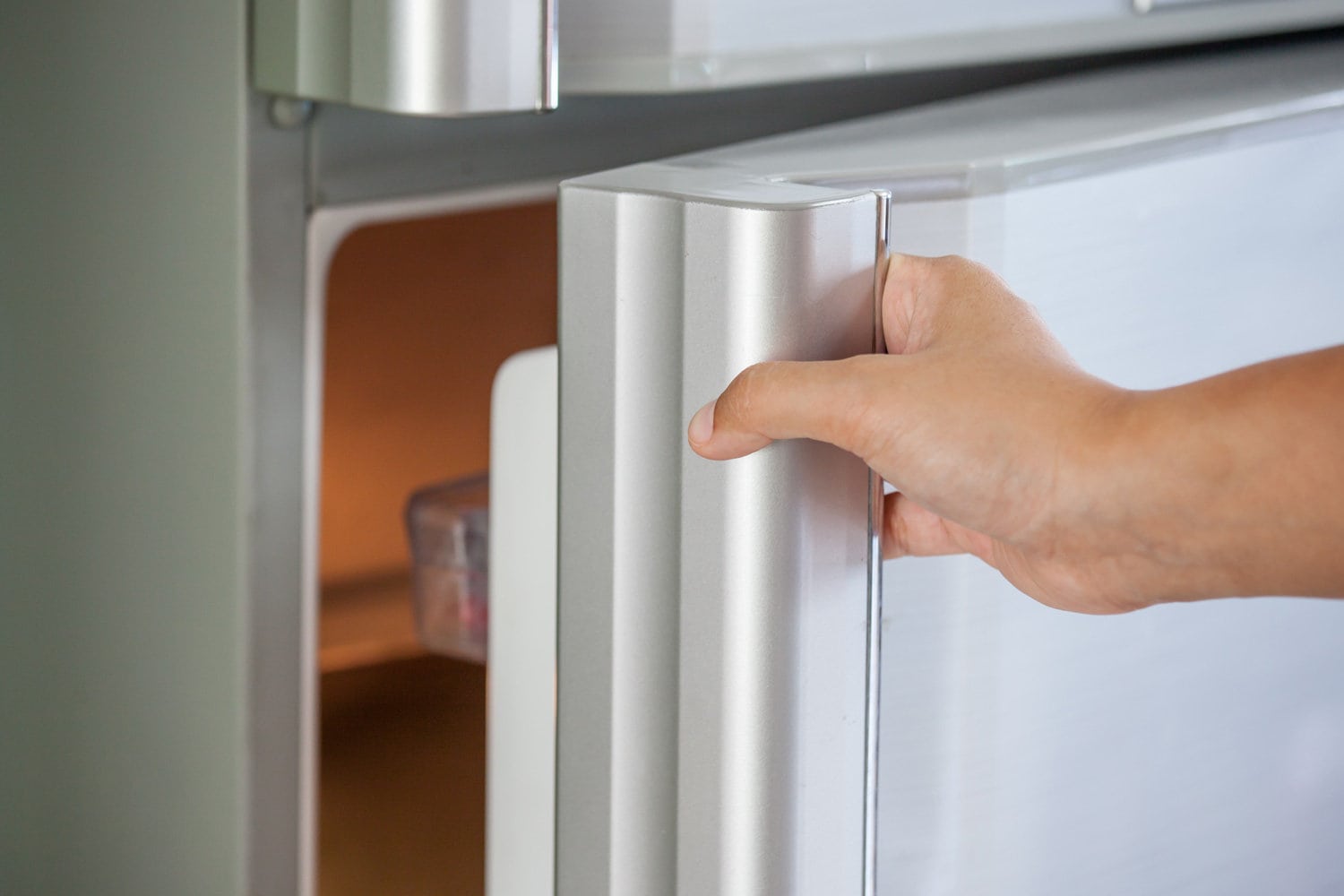 Woman hand opening a refrigerator door