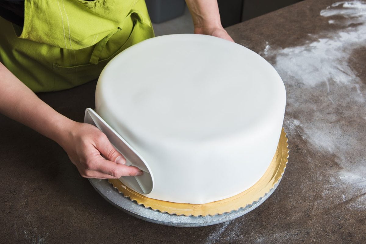 Woman shaping a perfectly smooth Royal Iced cake