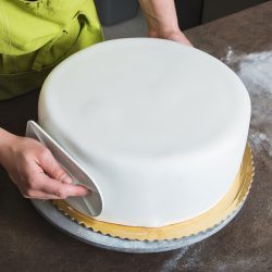 Woman shaping a perfectly smooth Royal Iced cake, How To Store A Royal Iced Cake