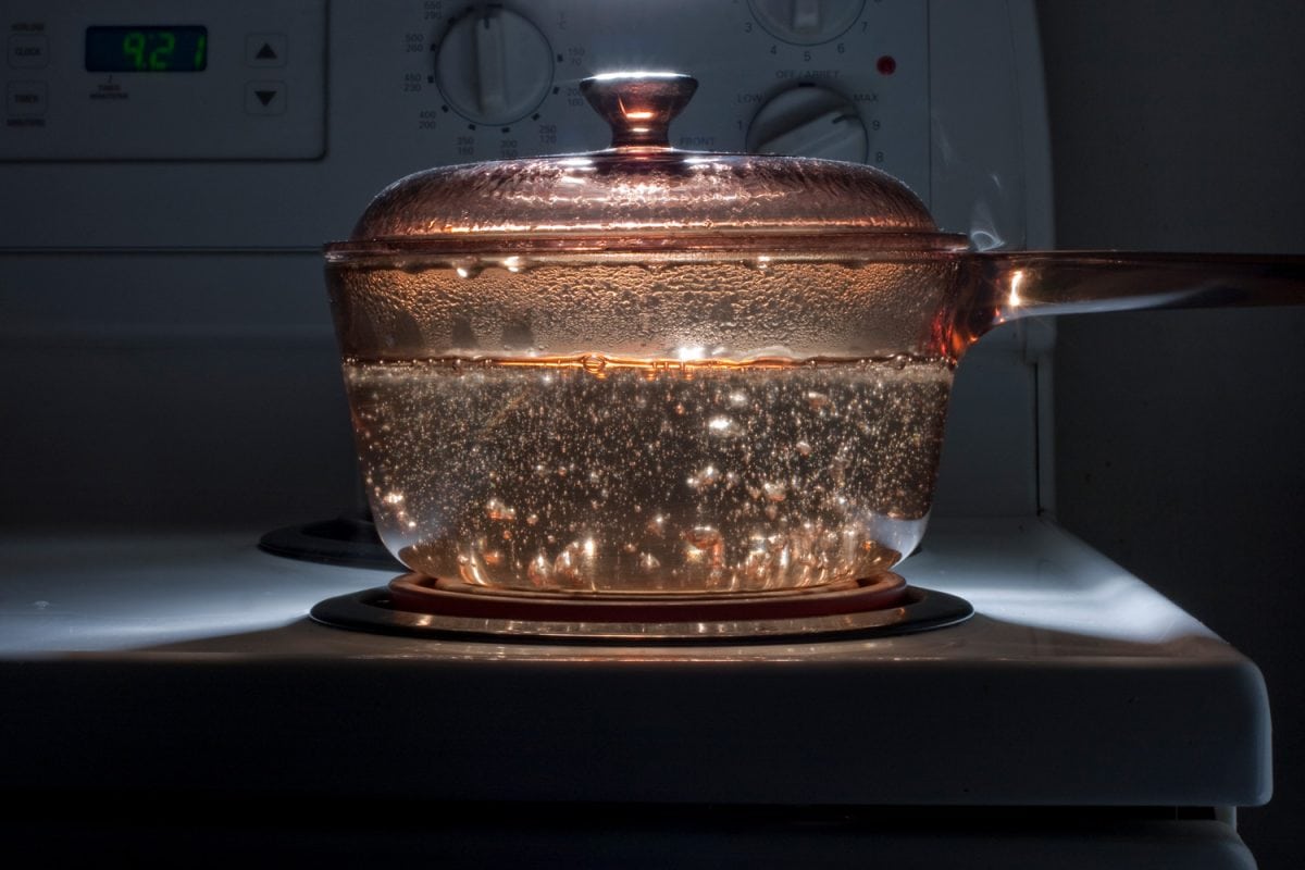 A saucepan of boiling water on a hob in a dark room