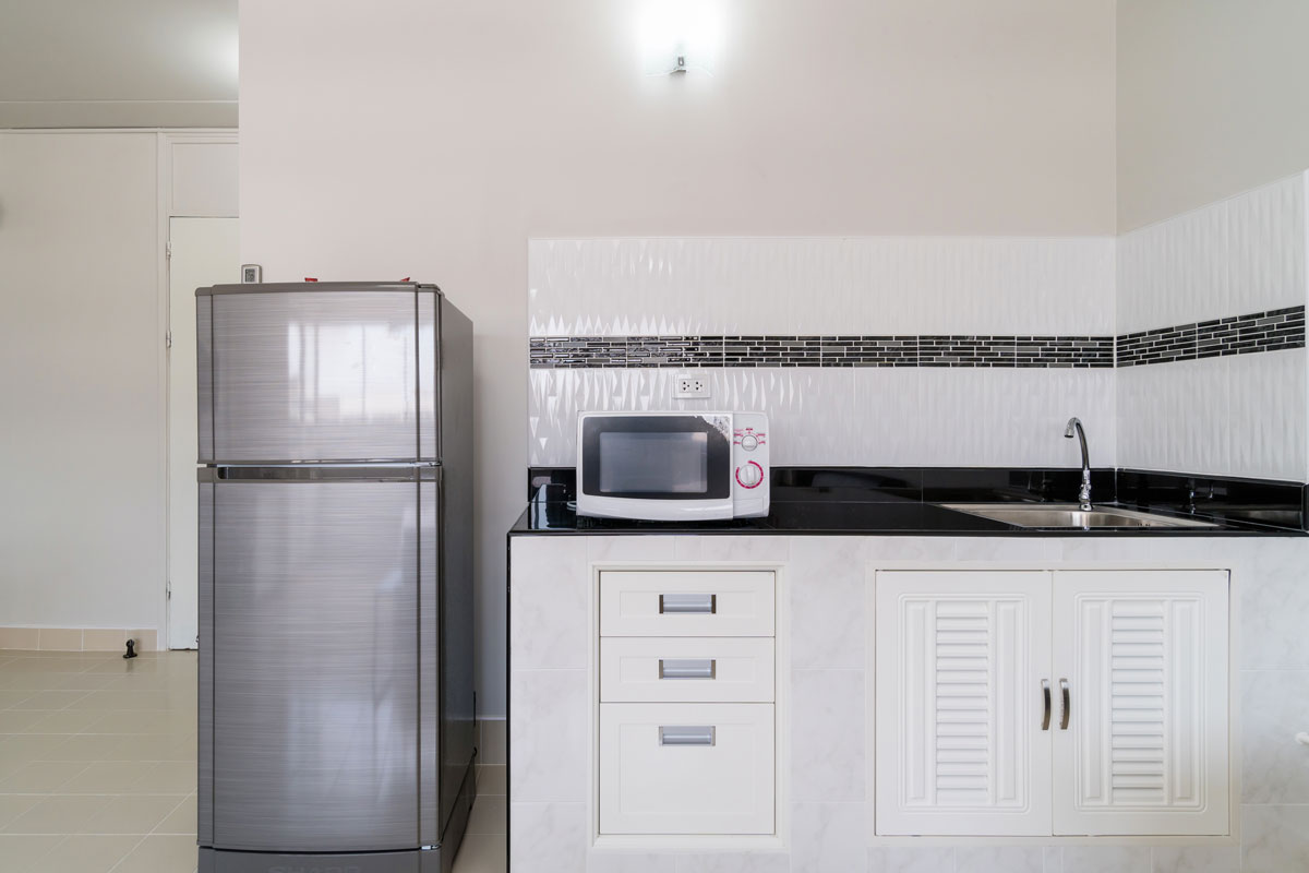 A small apartment kitchen with white cabinets and white tile backsplash