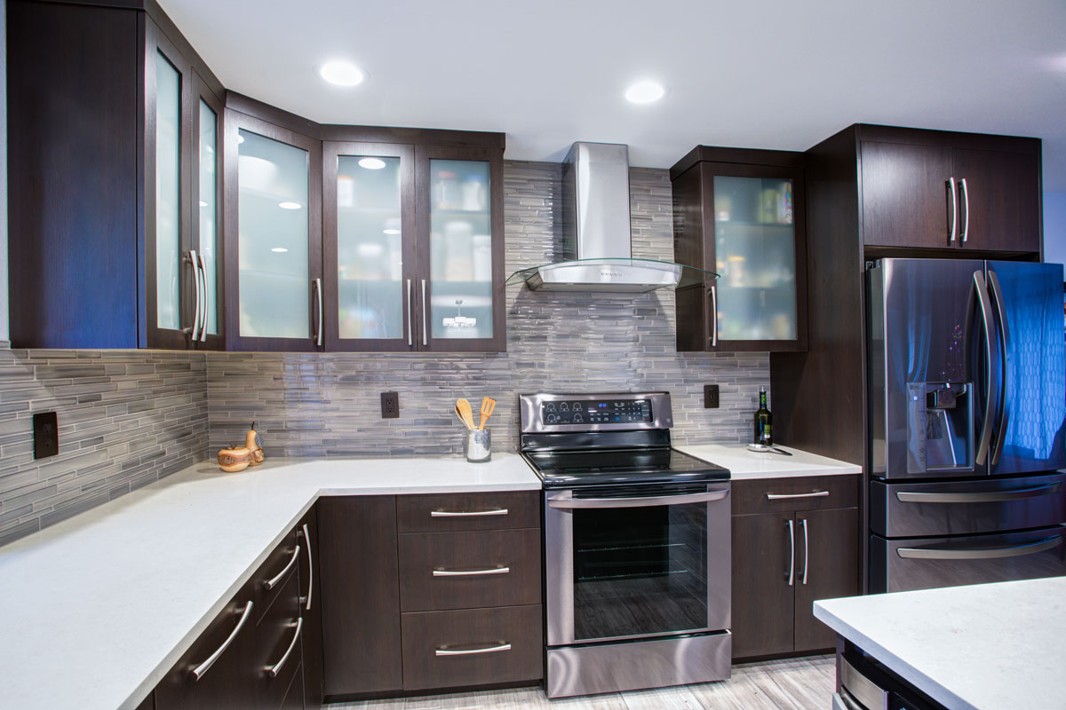 Beautiful bright themed kitchen with white countertops and brown cabinets matched with gray and brown tiled backsplash