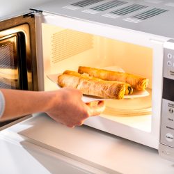 Close-up of a woman baking pastry in microwave oven.