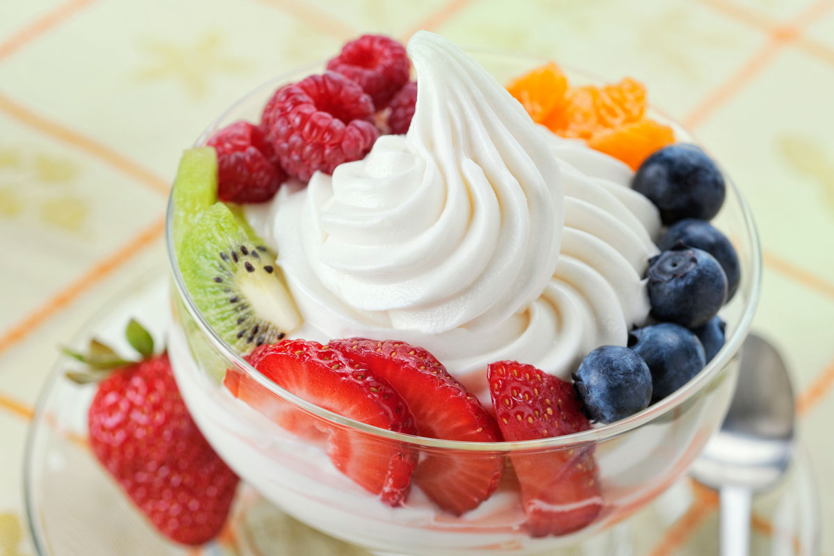 DIsh of vanilla soft-serve frozen yogurt surrounded by a variety of fresh fruits