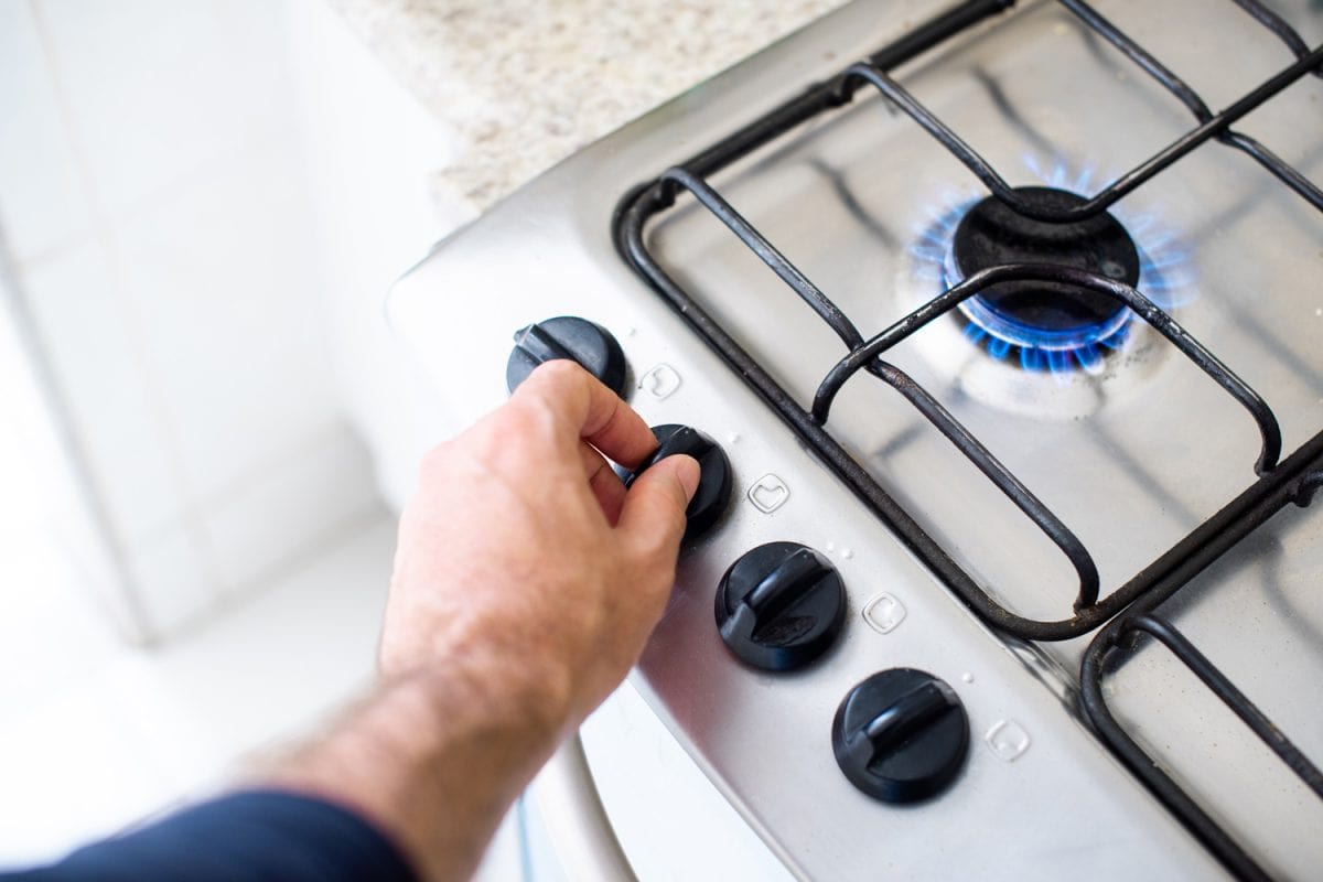 Hands of a man turning knob to light a gas stove