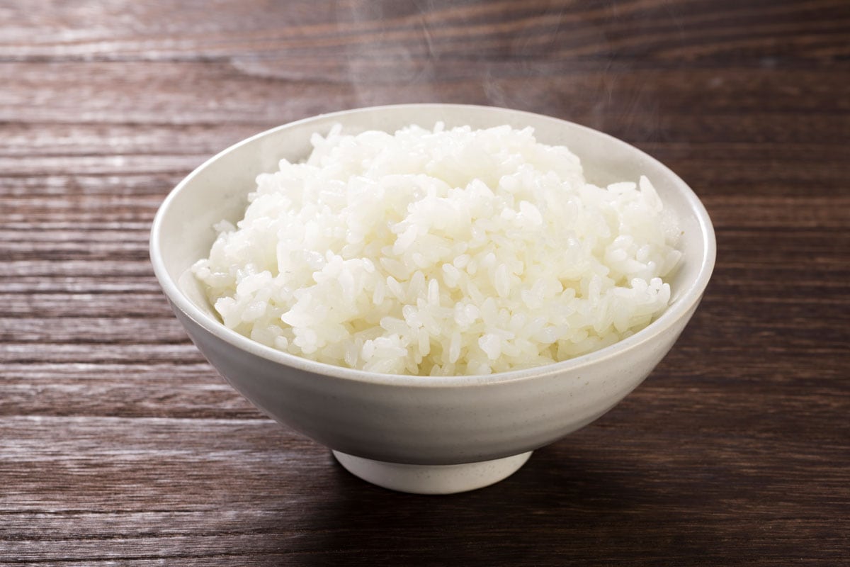 Japanese white rice in a white bowl in a wooden desk
