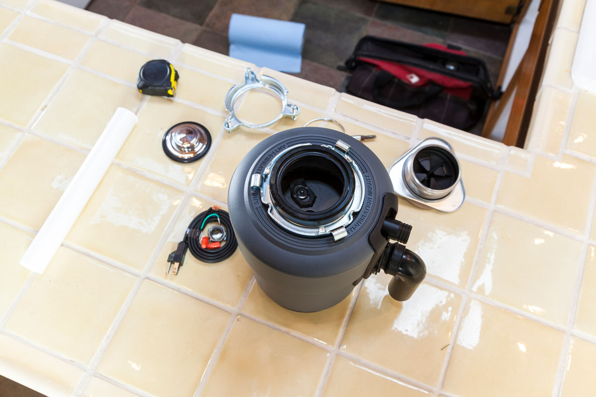 Man installing garbage disposal in home, How Long Does a Garbage Disposal Last?