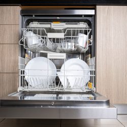 Open door of built-in dishwasher. Kitchen with integrated appliances. Plates and dishes in the dishwasher - How Long Does a Kenmore Dishwasher Run