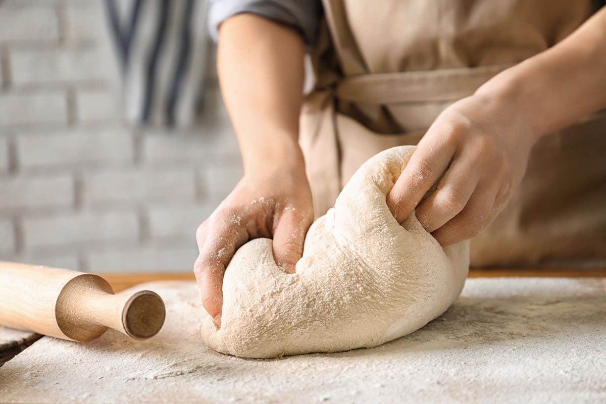 Pastry chef kneading dough on the table