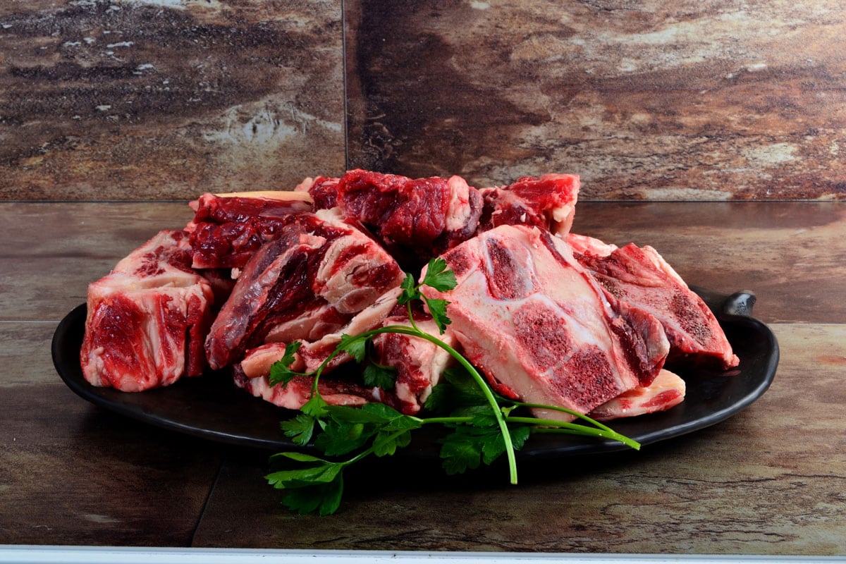 Raw meat with bone on clay plate and brown stone background, How To Cut Beef Bones At Home