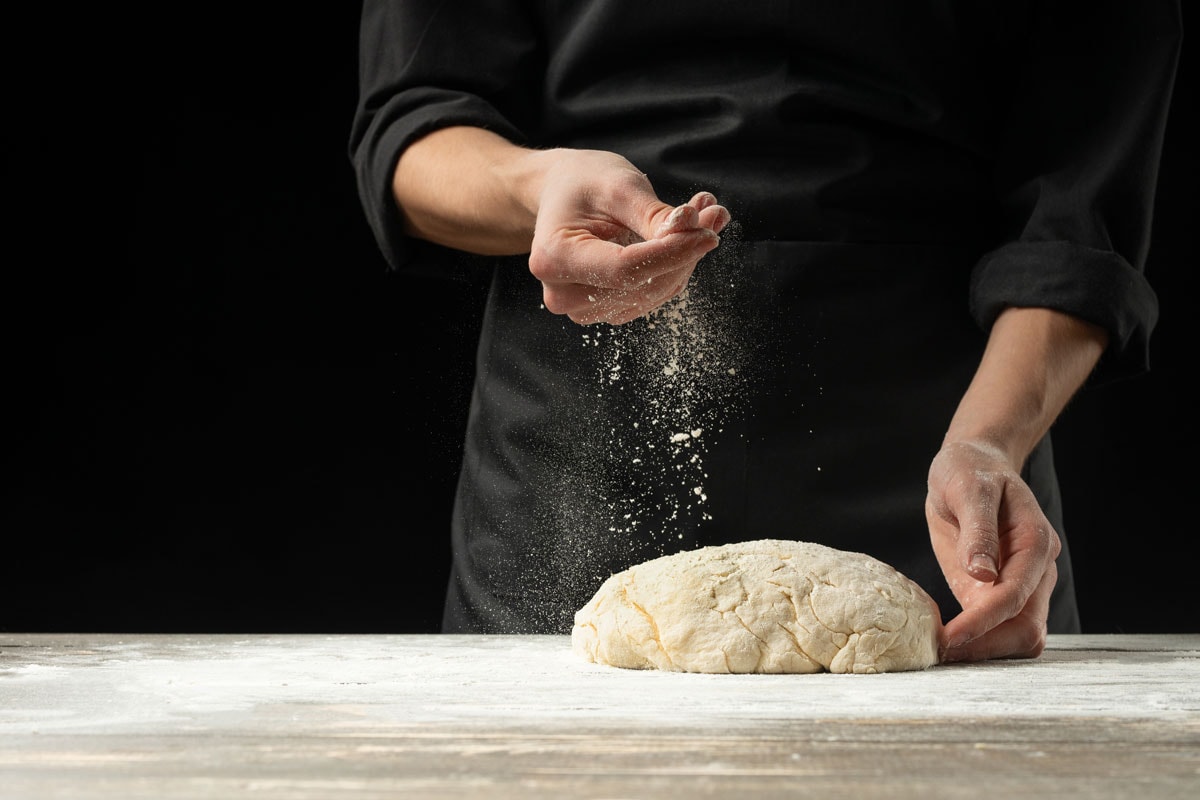 Spraying flour on the dough before kneading it