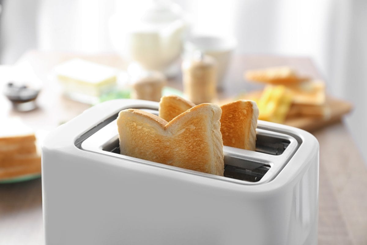 Toaster with tasty breakfast toasts on table