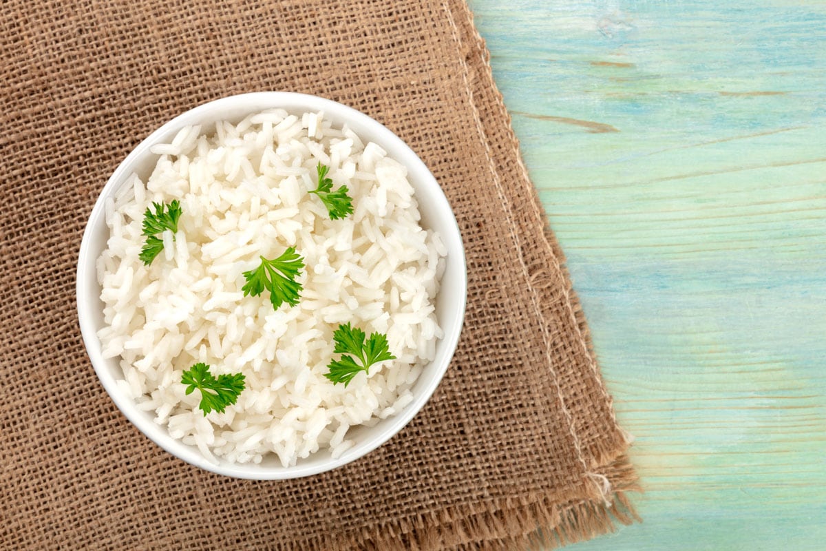 bowl of cooked white long rice, shot from the top on rustic textures