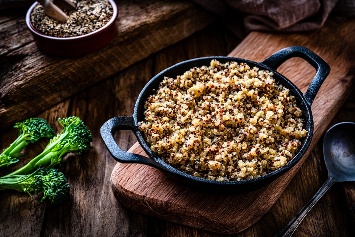 cooked quinoa in a cast iron pan shot on rustic wooden table