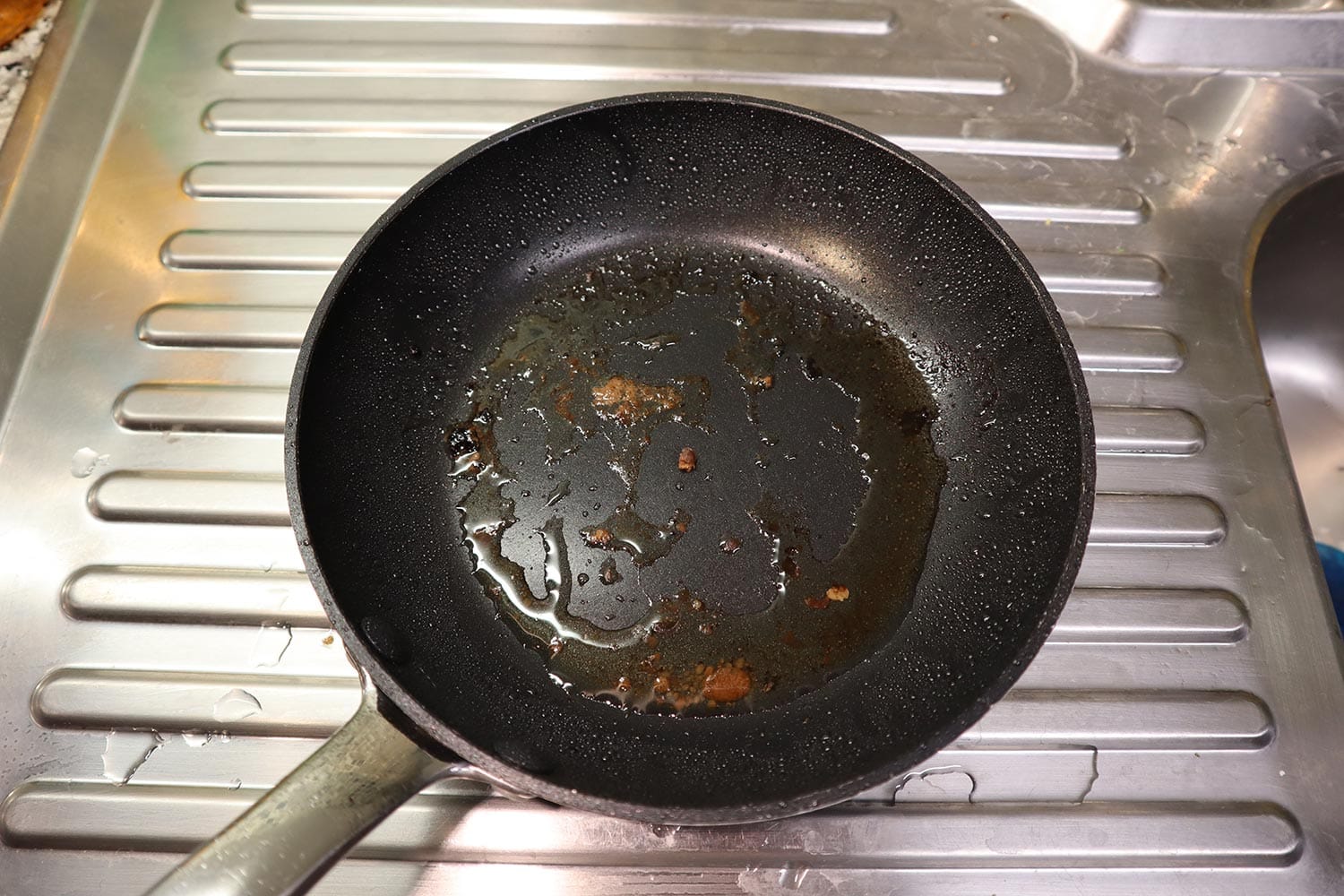 A black dirty non stick frying pan with grease splatter and food residue