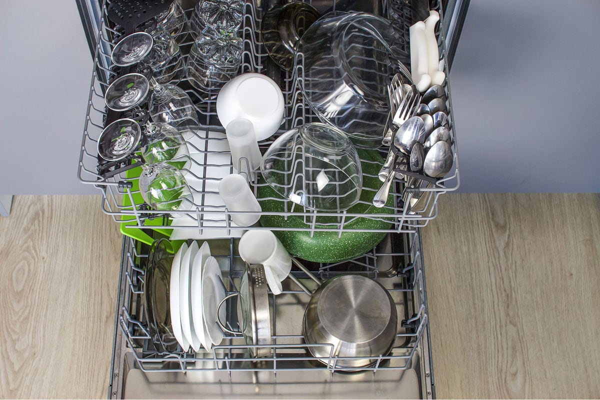 An opened dishwasher filled with kitchen utensils