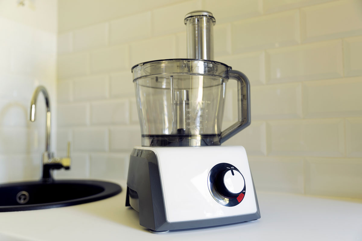 Electric food processor on kitchen countertop, kitchen sink