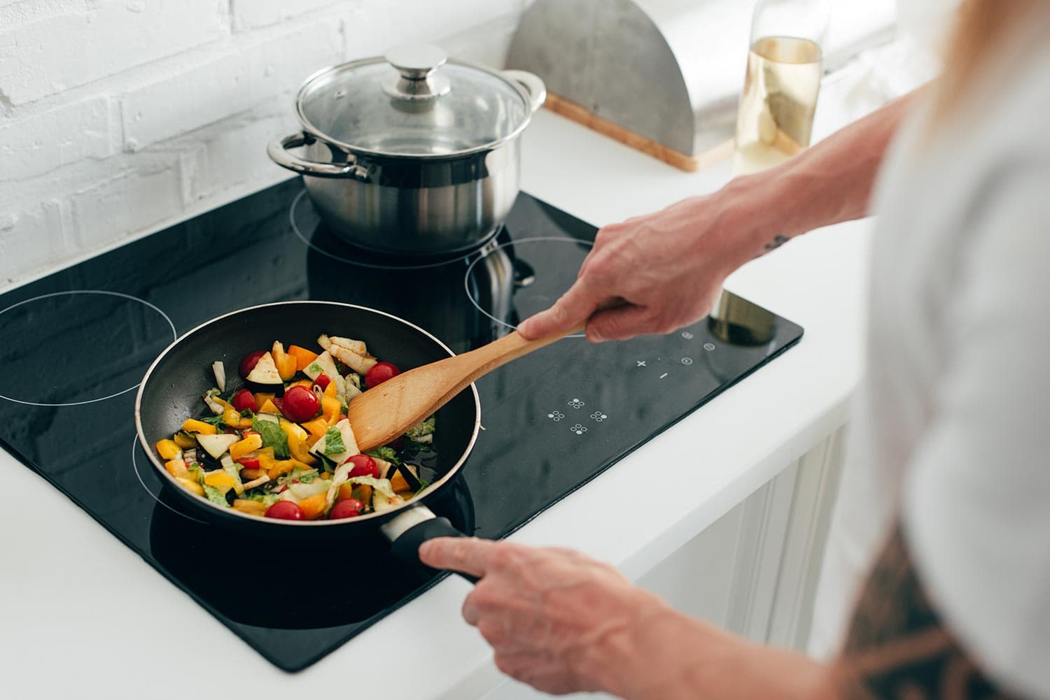 Man cooking vegetables in frying pan on electric stove