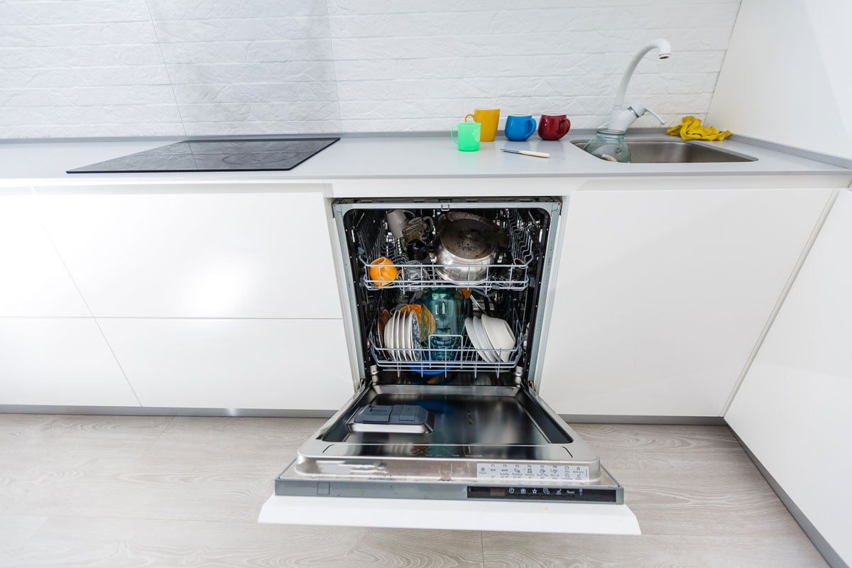 Open dishwasher with clean dishes at home kitchen