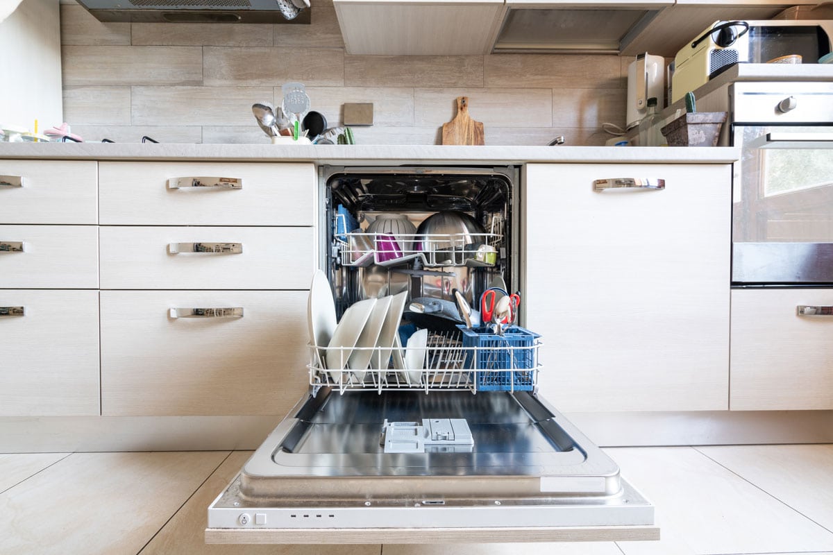 Opened dishwasher filled with kitchen utensils