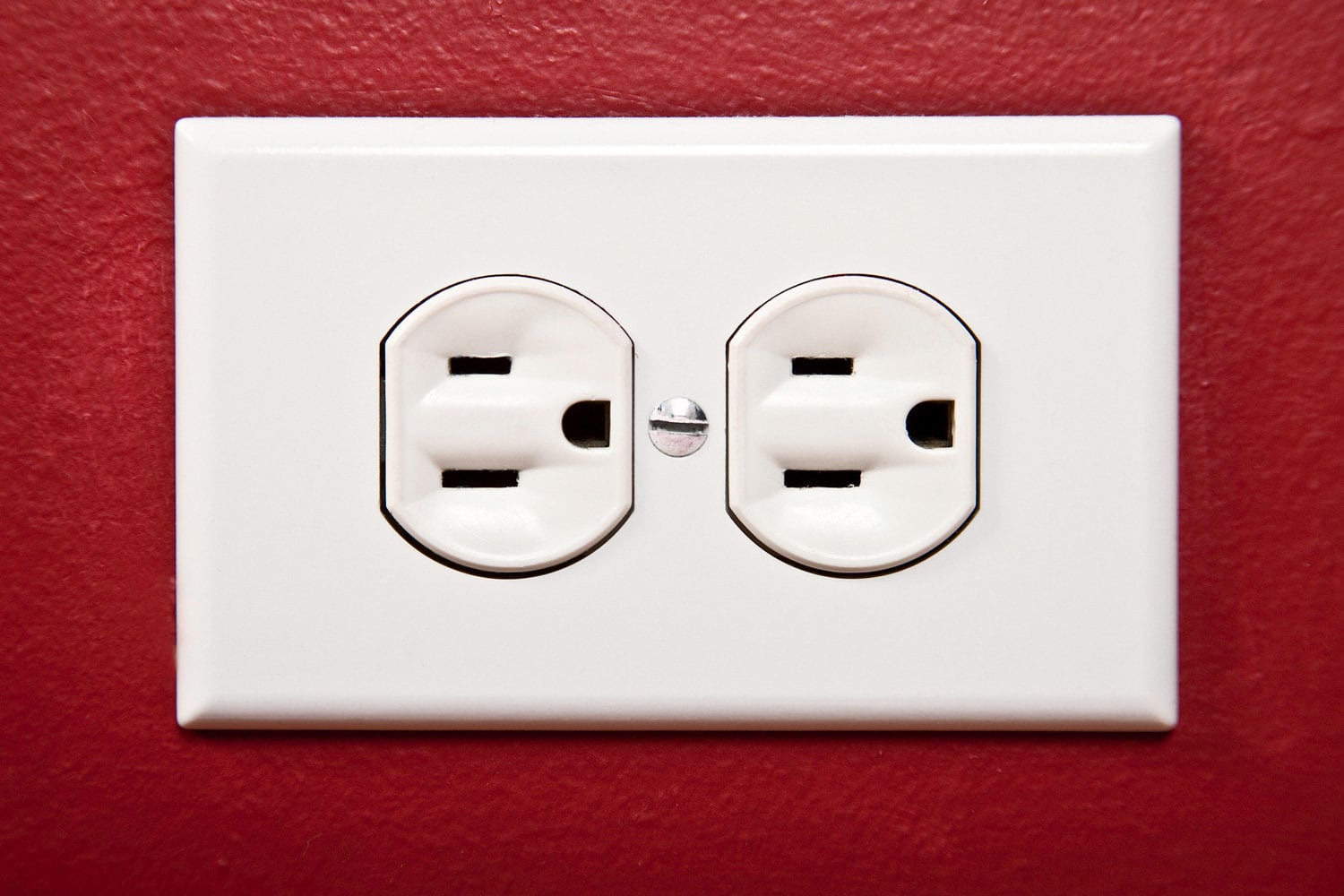 White electric outlet on a red wall.
