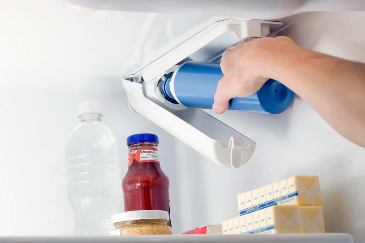 Woman changing the water filter system of the refrigerator